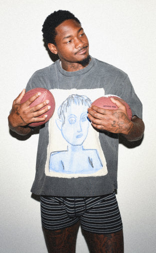 Stefon Diggs holding two footballs to his chest while wearing the Ultra Super Soft Boxer Brief in Black Crew Stripe