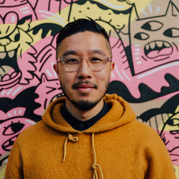 Photo of illustrator Geo Law in front of his artwork