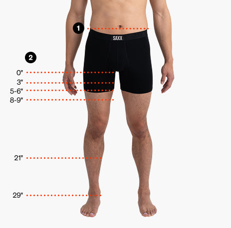 Front view of a model wearing black SAXX boxer briefs with visual measurement guides showing waistband position, inseam lengths from 0 to 9 inches.