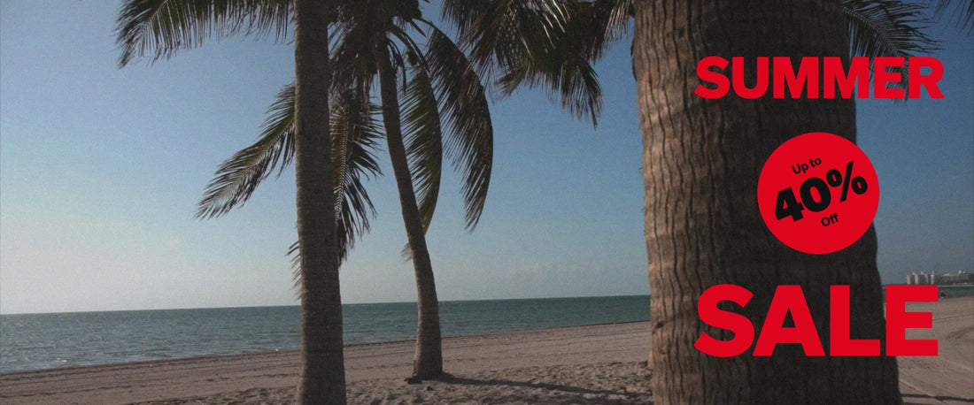 A photo of a golden sand beach shoreline with a palm tree trunk in the foreground. 