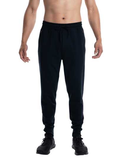Shirtless man in black pants and shoes standing with arms at side
